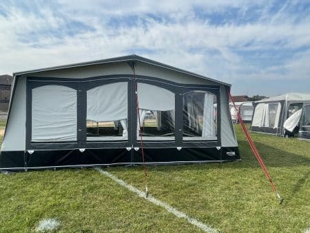 A tent is pitched on the grass in front of some buildings.