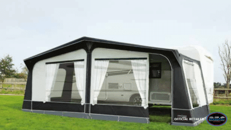 A black and white tent with a green field in the background.