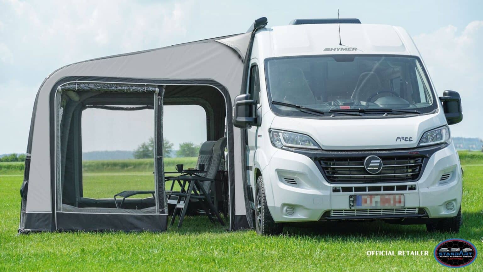 A white van parked in the grass near a tent.