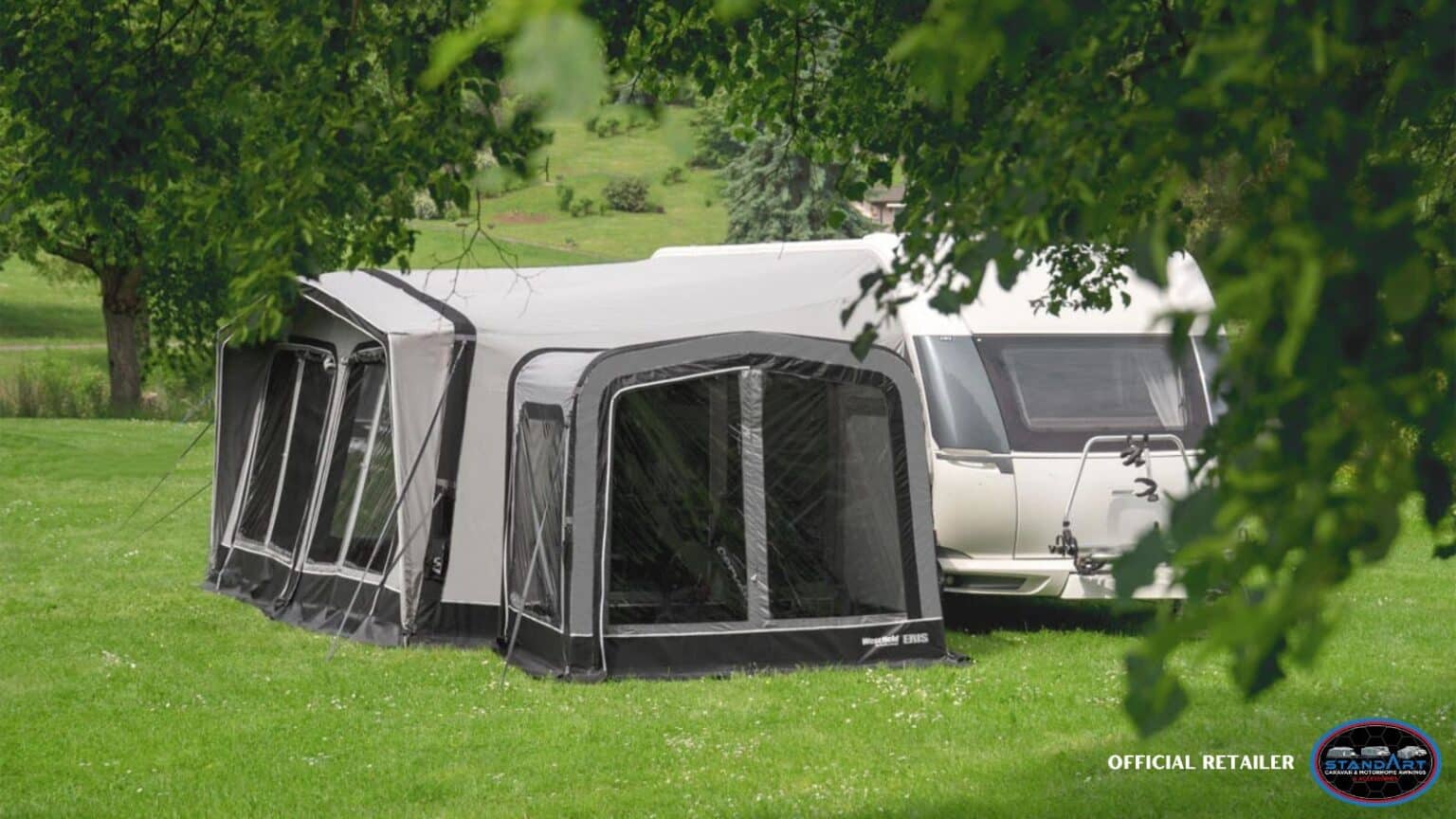 A group of tents in the grass next to trees.